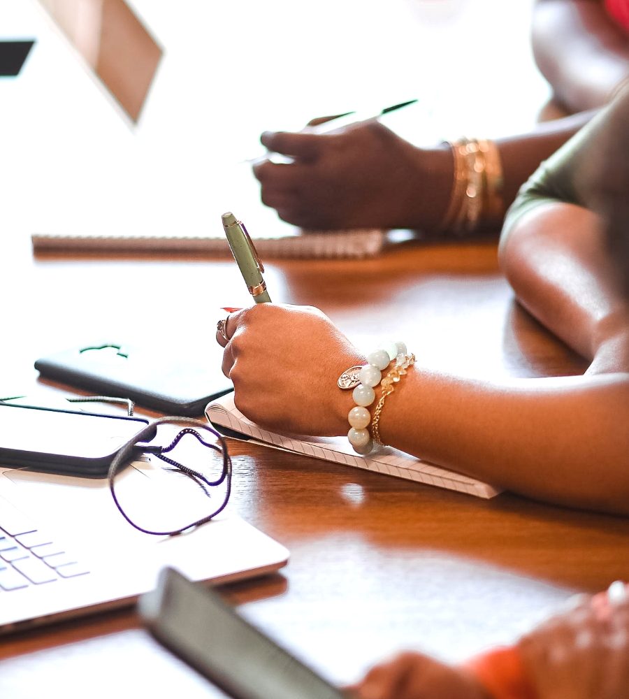 Black women executives taking notes in a board meeting