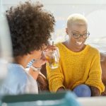 two black women living boldly over 40. Having a drink and conversation in a casual setting.