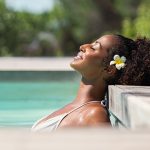 black woman soaking in sun while relaxing in pool